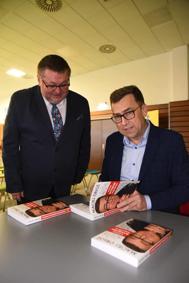 Maciej Orloś podpisujący książki przeznaczone na cele charytatywne